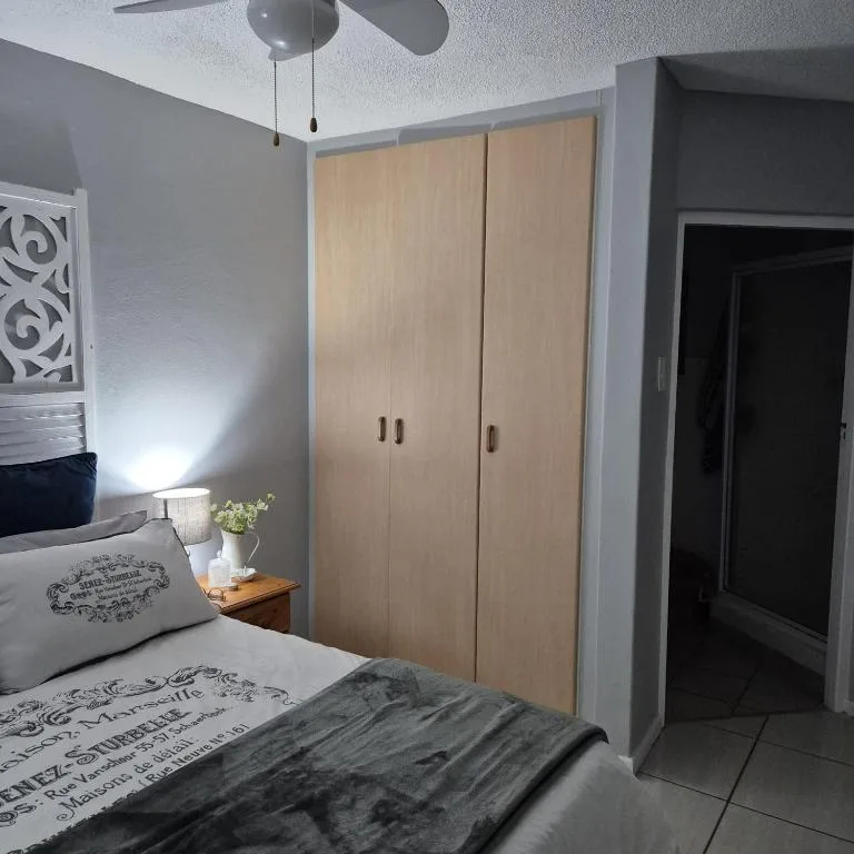 Modern bedroom with double bed, wooden wardrobe, and ceiling fan