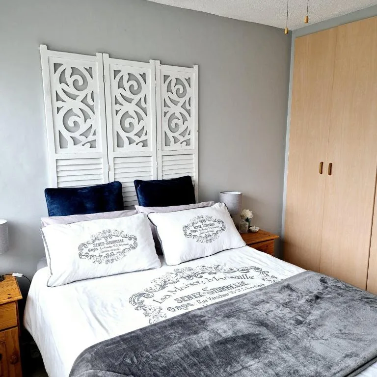 Elegant bedroom with queen bed, navy pillows, ornate white headboard, wooden wardrobe