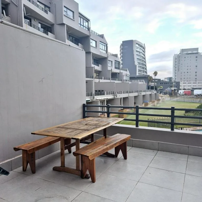 Wooden picnic table and benches on paved outdoor balcony area