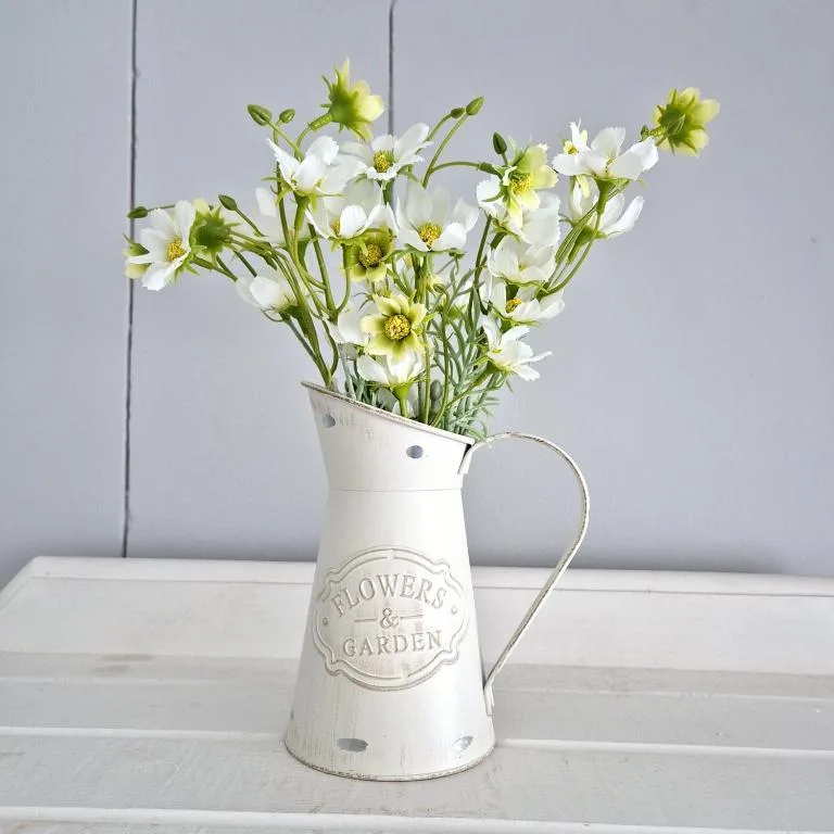 White ceramic pitcher with fresh white and yellow flowers on windowsill