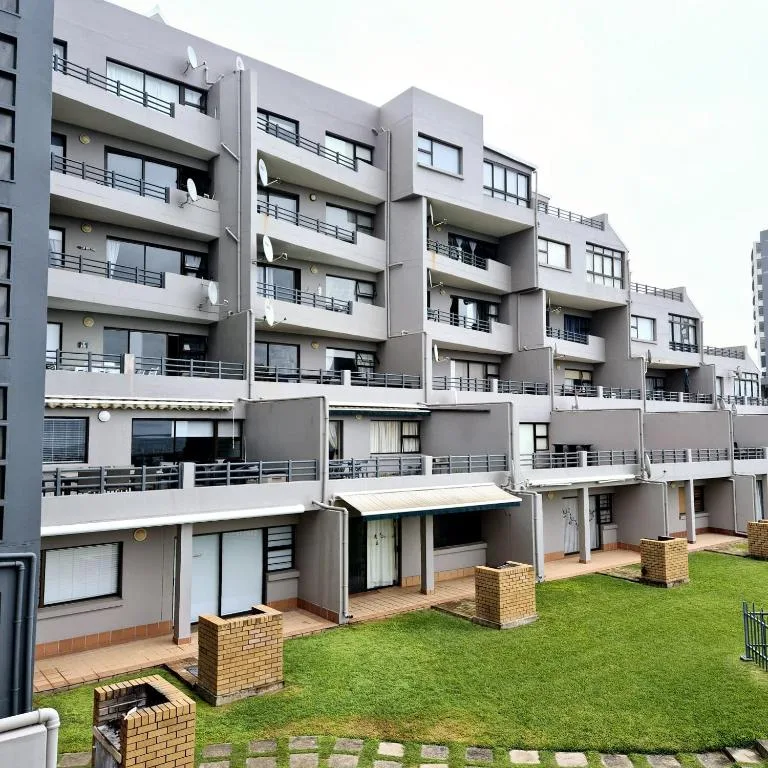 Modern multi-story apartment building with balconies and green courtyard lawn