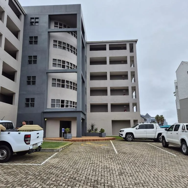 Modern multi-story apartment building with paved parking area and vehicles