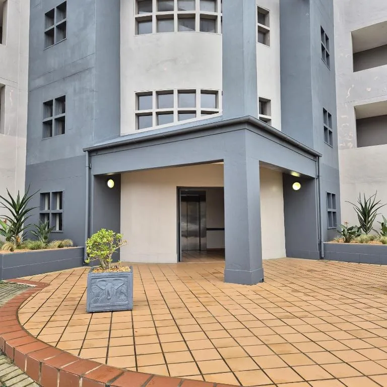 Modern apartment building entrance with tiled courtyard and potted plants