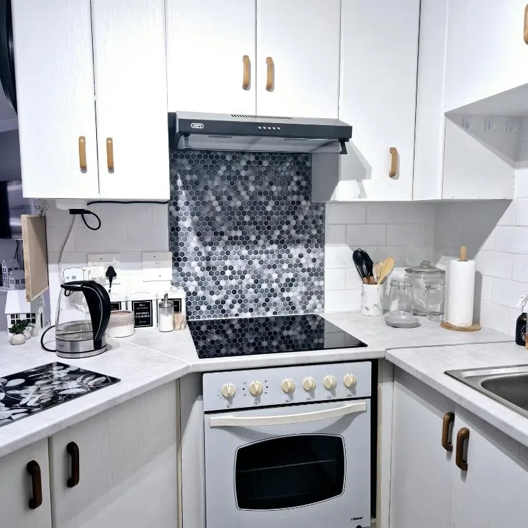Modern kitchen with white cabinetry, stove, and geometric backsplash tile