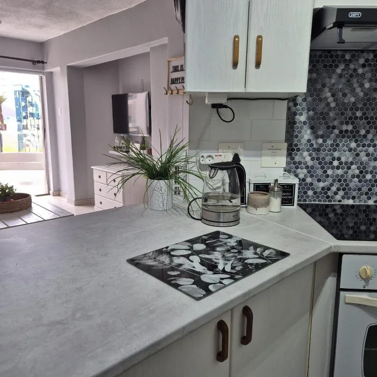 Modern kitchen with white cabinetry, geometric backtile, and light countertops