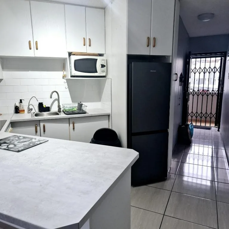 Modern kitchen with white cabinetry, black refrigerator, and marble countertop