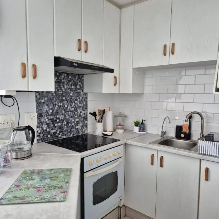 Modern white kitchen with geometric backsplash, stainless appliances, and wood handles