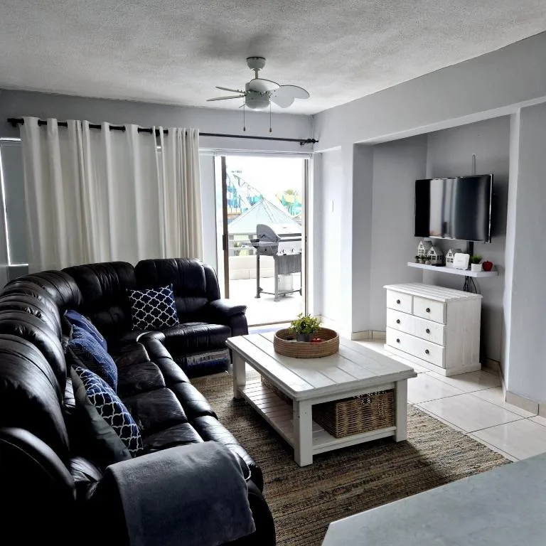 Modern lounge with black leather sofa, white TV console, and deck access