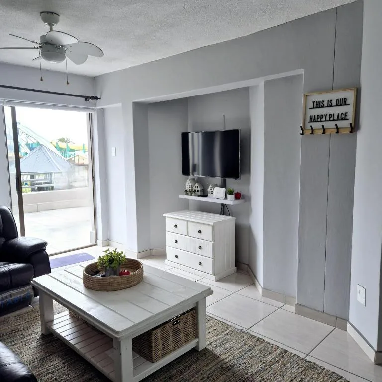 Modern lounge with TV, white furnishings, and access to deck area
