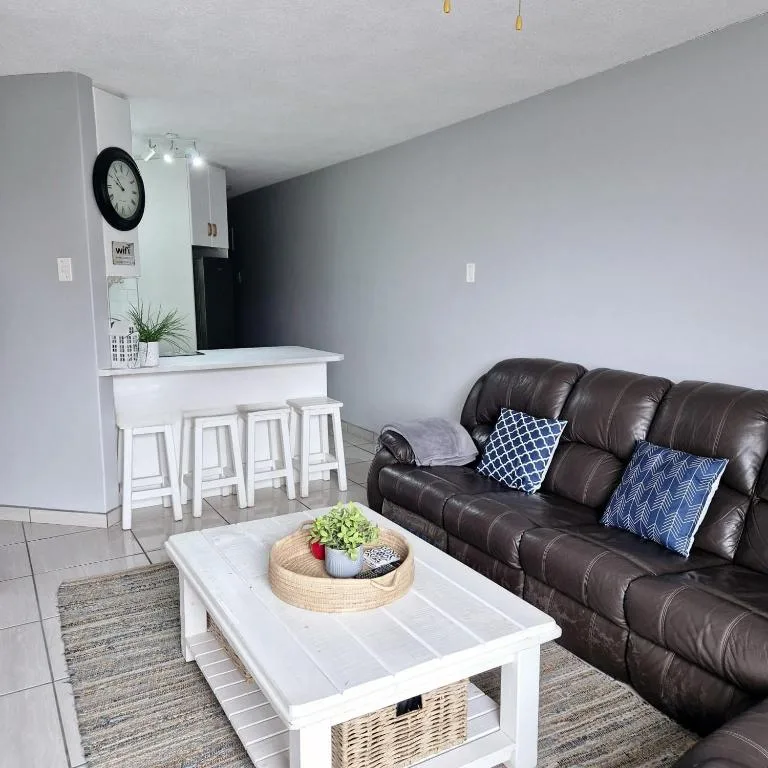 Modern lounge with brown leather sofa, white coffee table, and kitchen bar behind