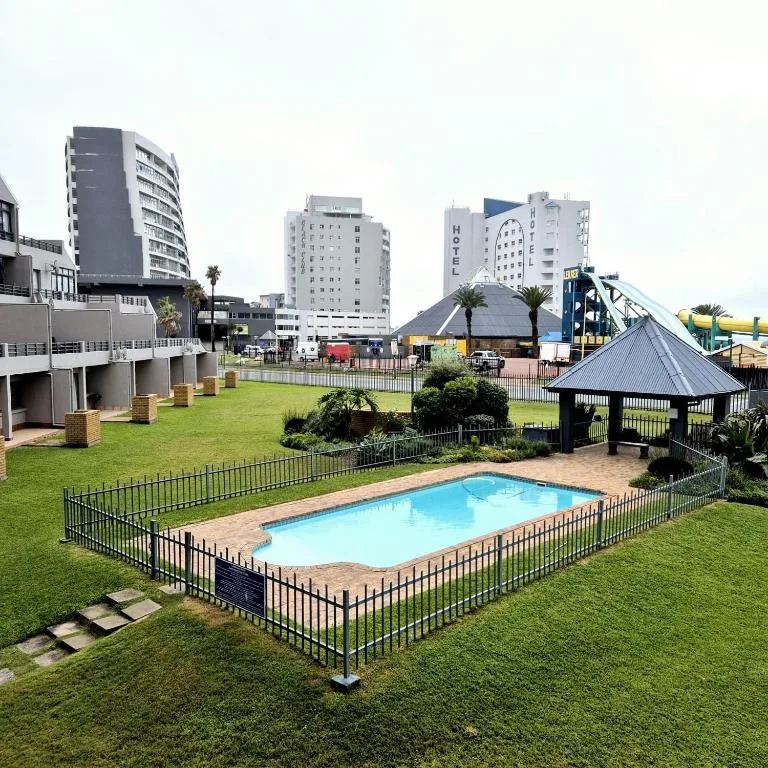 Rectangular swimming pool on manicured lawn with black fencing and gazebo
