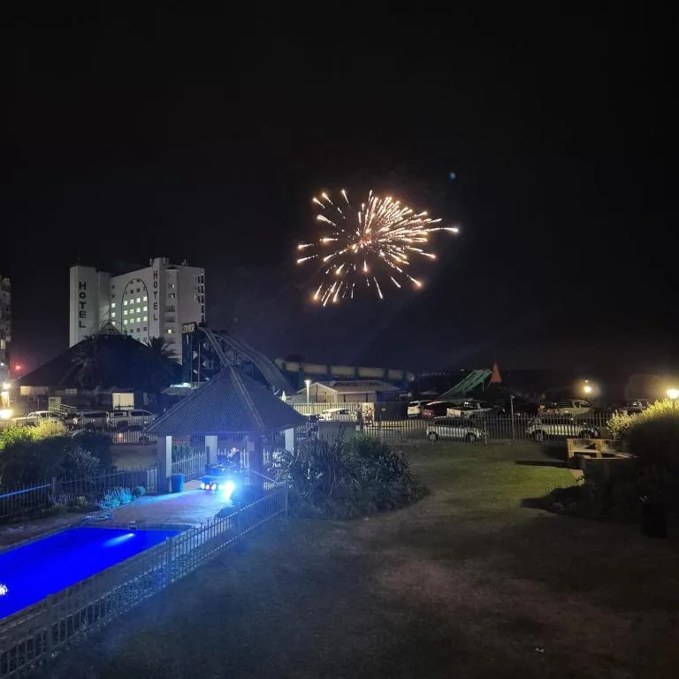 Night view of illuminated pool and property with fireworks bursting overhead