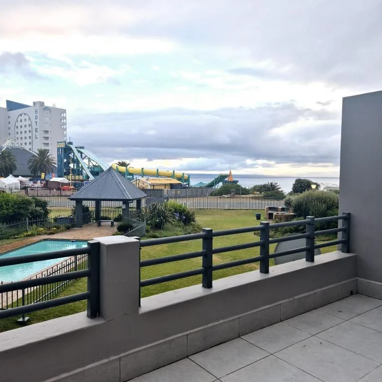 Scenic coastal view with pool, gardens, and distant water from balcony