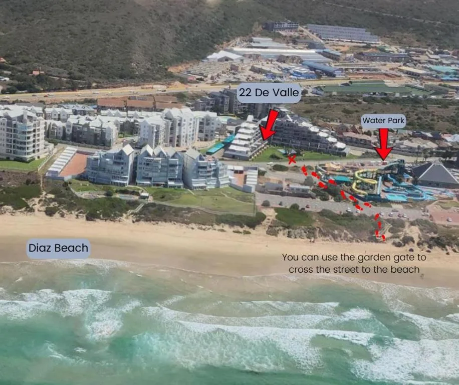 Aerial view of beachfront property with ocean waves and coastal town below