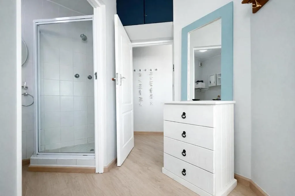 Modern bathroom with shower enclosure, white vanity, and turquoise mirror frame