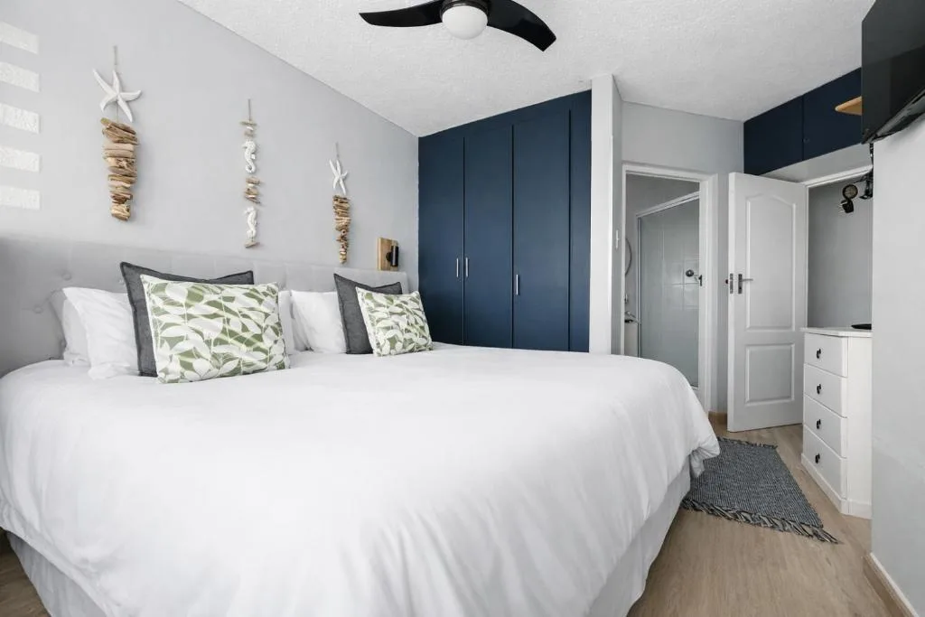 Modern bedroom with queen bed, navy wardrobe, and coastal decor accents