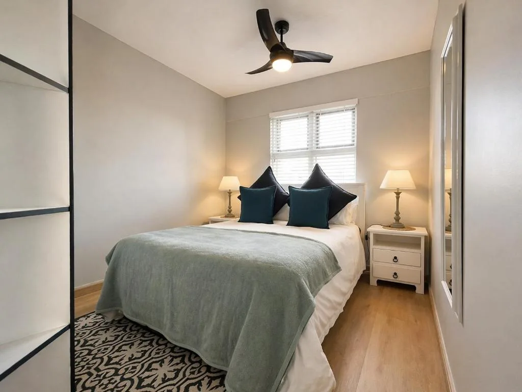 Bright bedroom with queen bed, black pillows, bedside lamps, ceiling fan