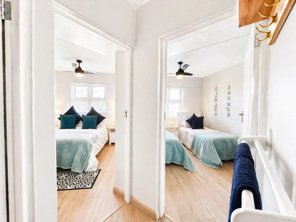 Two bright bedrooms with single beds, teal accents, and natural light