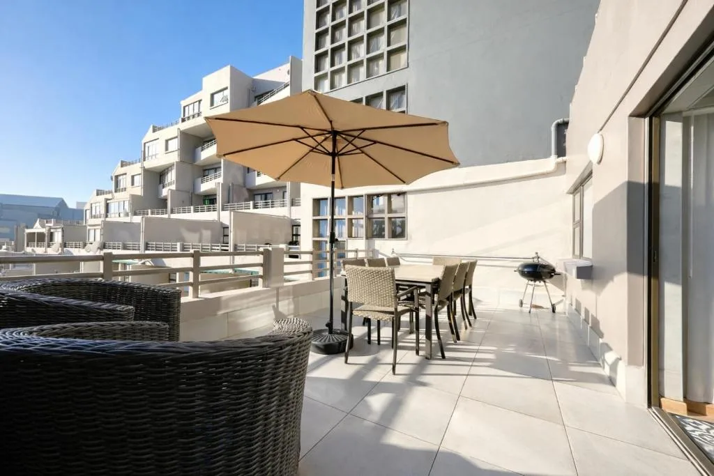 Spacious patio with umbrella, dining table, and wicker seating area