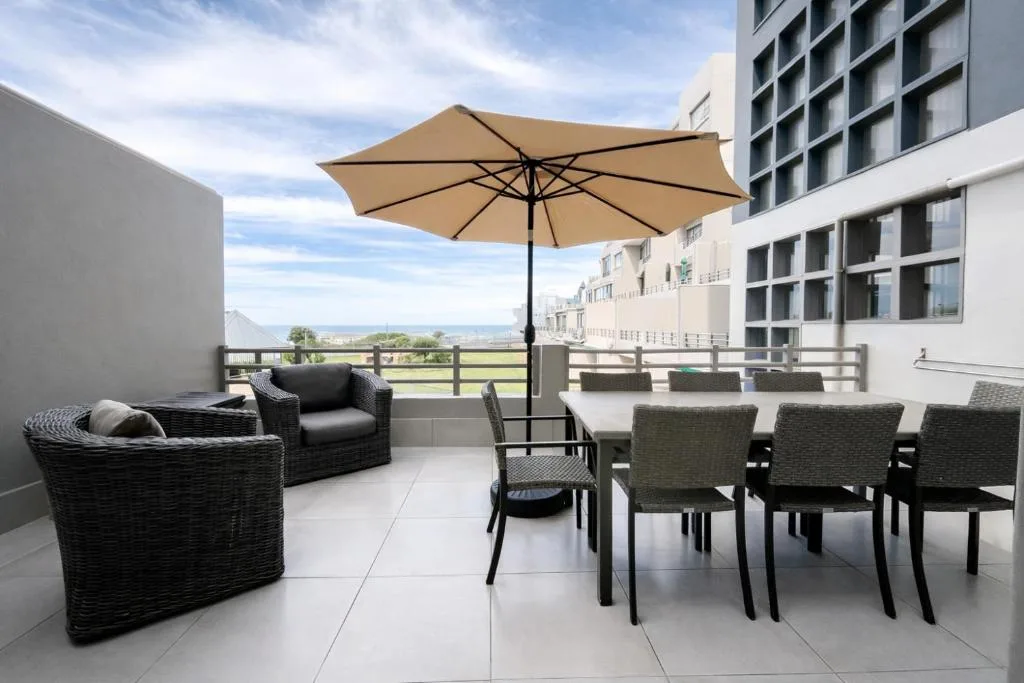 Spacious outdoor deck with seating, umbrella, and panoramic coastal views