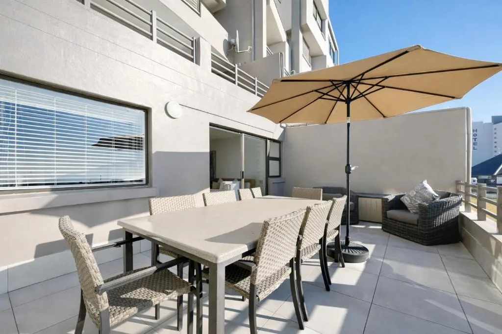 Modern patio with dining table, tan umbrella, and lounge seating area