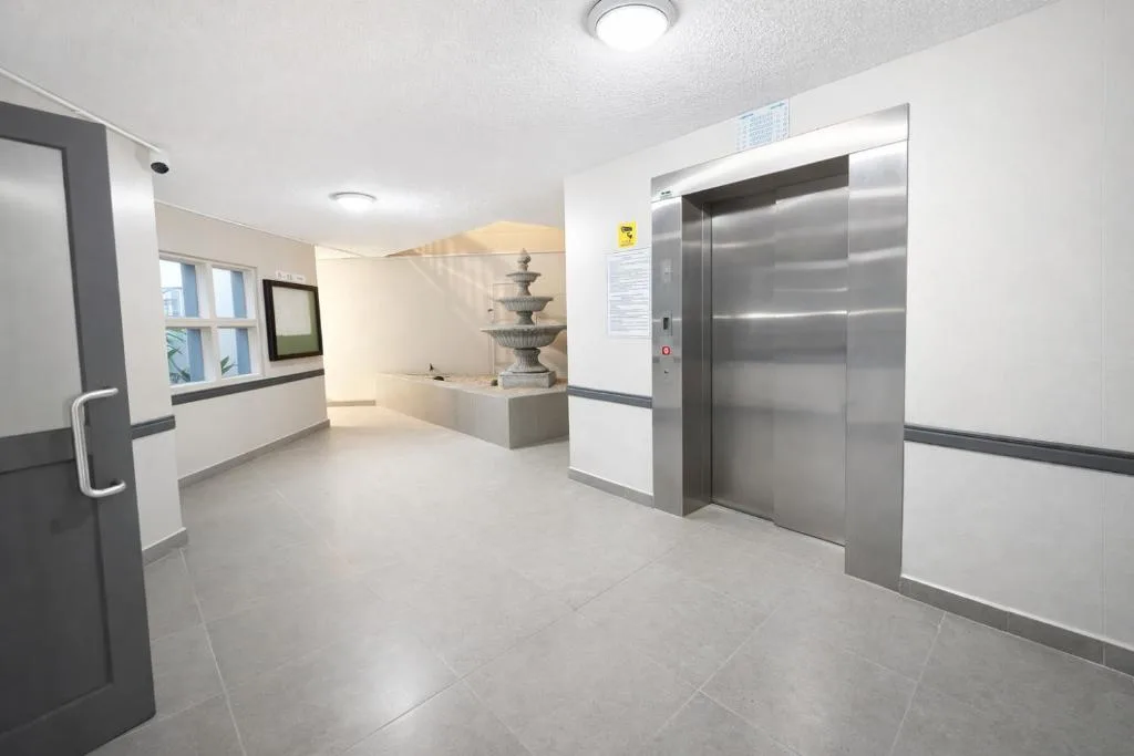 Modern building lobby with elevator, reception desk, and decorative fountain