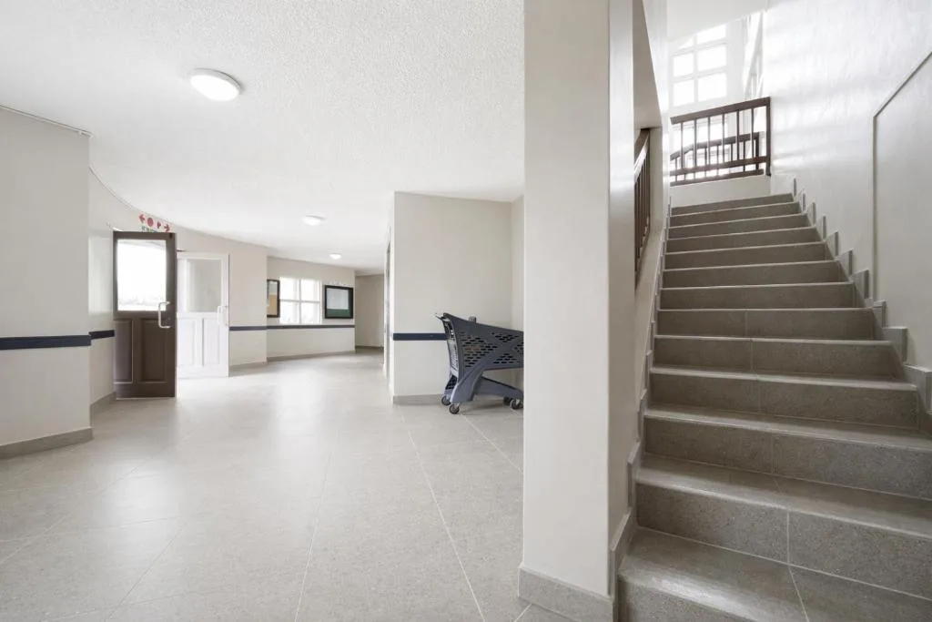 Bright interior hallway with stairs, tiled flooring, and modern white walls