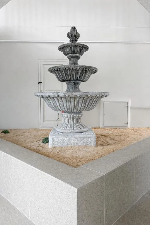 Ornate tiered stone fountain in courtyard with white walls