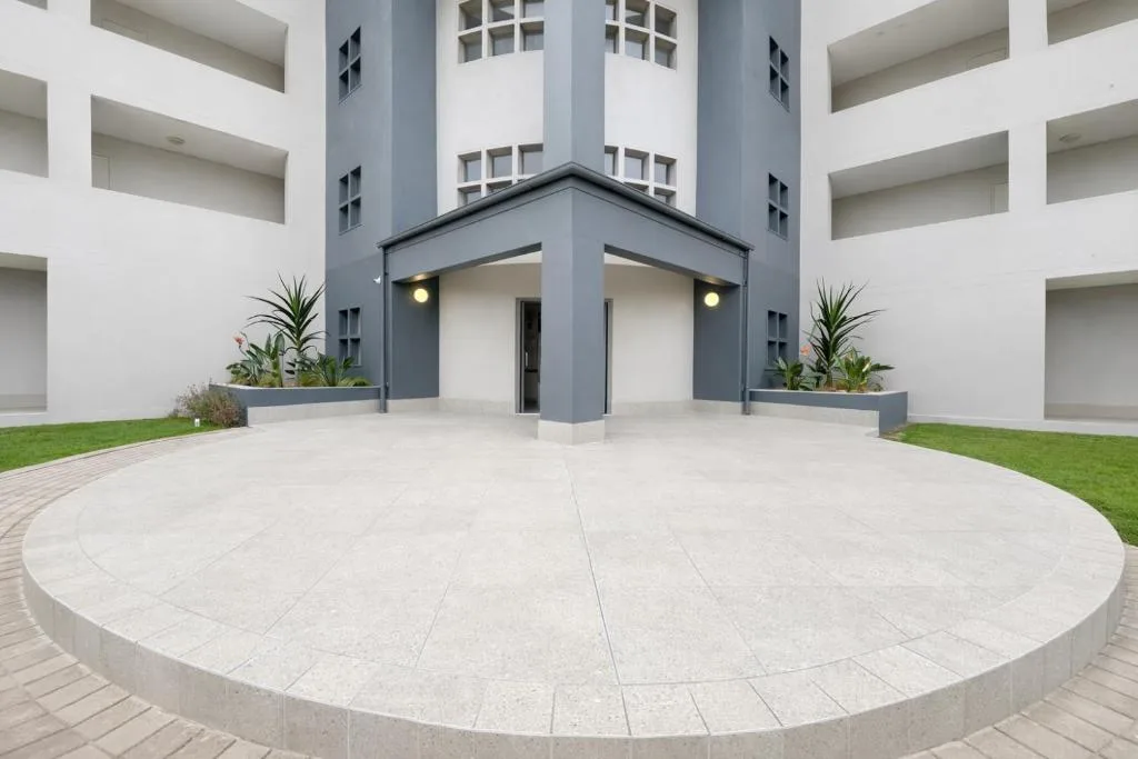 Modern apartment building entrance with circular paved courtyard and landscaping
