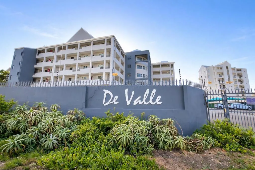 Multi-story De Valle apartment complex with white railings and blue signage