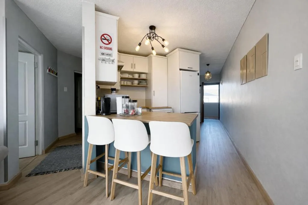 Modern kitchen with white cabinetry, breakfast bar seating, and stainless steel appliances