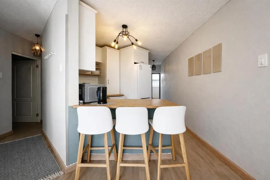 Modern kitchen with white cabinetry, wooden countertop, and three bar stools