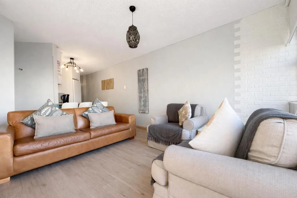 Spacious lounge with leather sofa, upholstered armchairs, and modern pendant lighting