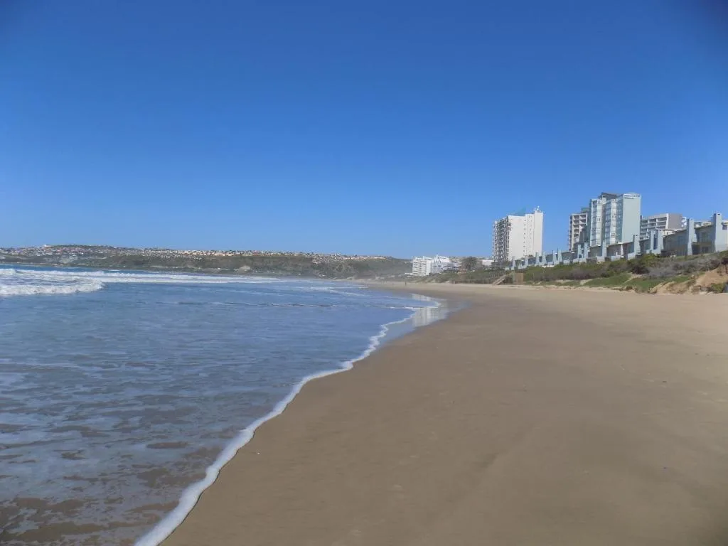 Sandy beach with ocean waves and beachfront apartments in background