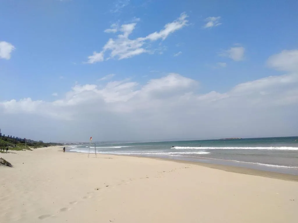 Wide sandy beach with turquoise waves and blue sky