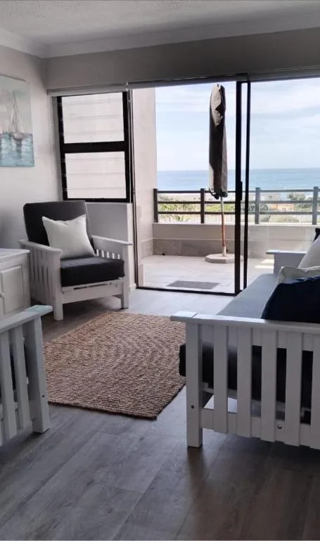 Bedroom with twin beds, chair, and ocean view through glass doors