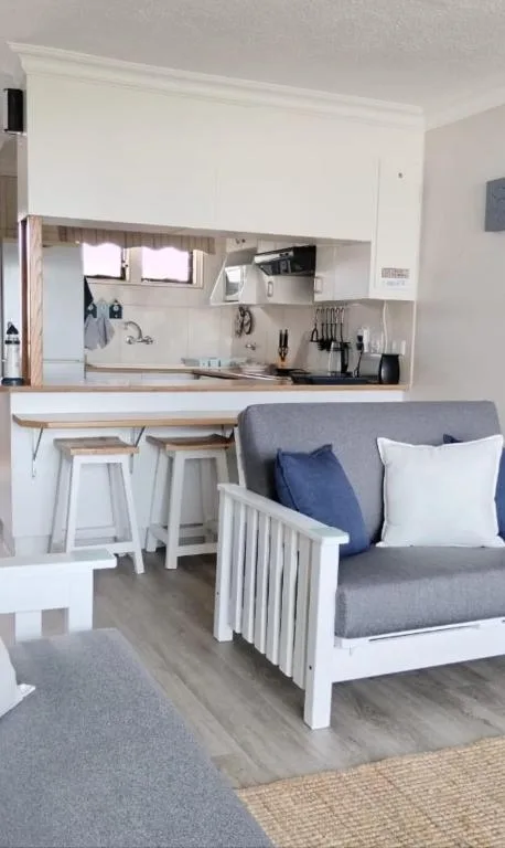 Modern open-plan kitchen with white cabinetry and breakfast counter seating