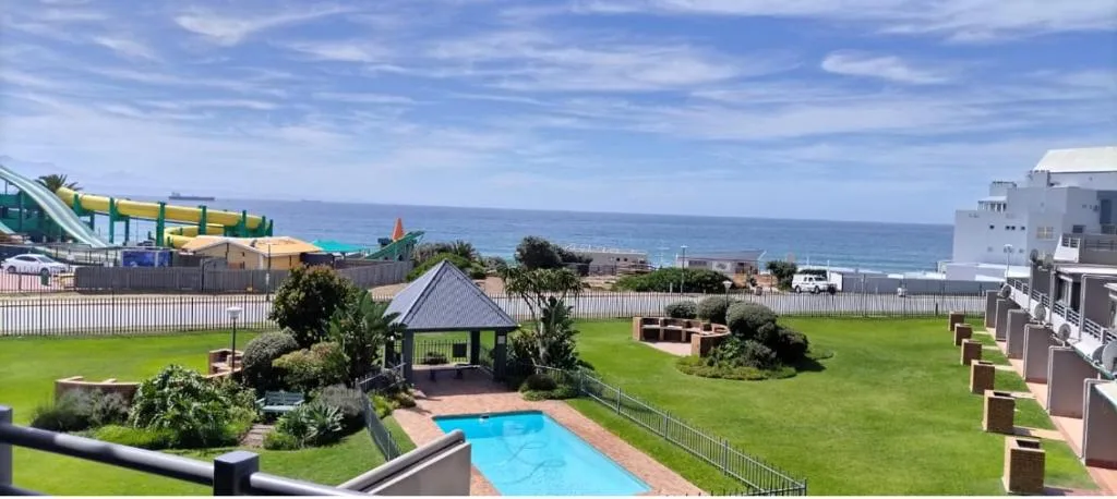 Bright blue swimming pool with ocean view in manicured garden setting
