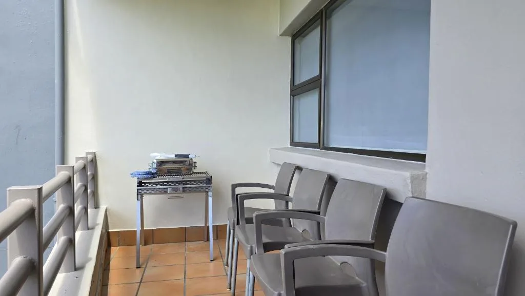Outdoor balcony with seating chairs and small braai grill setup
