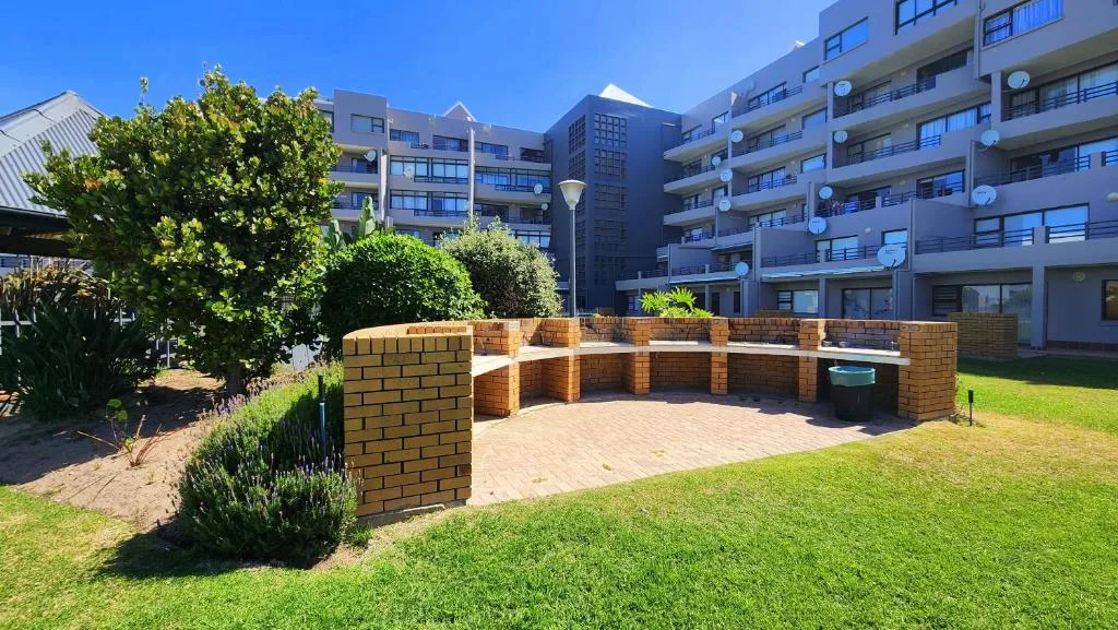 Brick braai area and seating zone in manicured garden with lawn