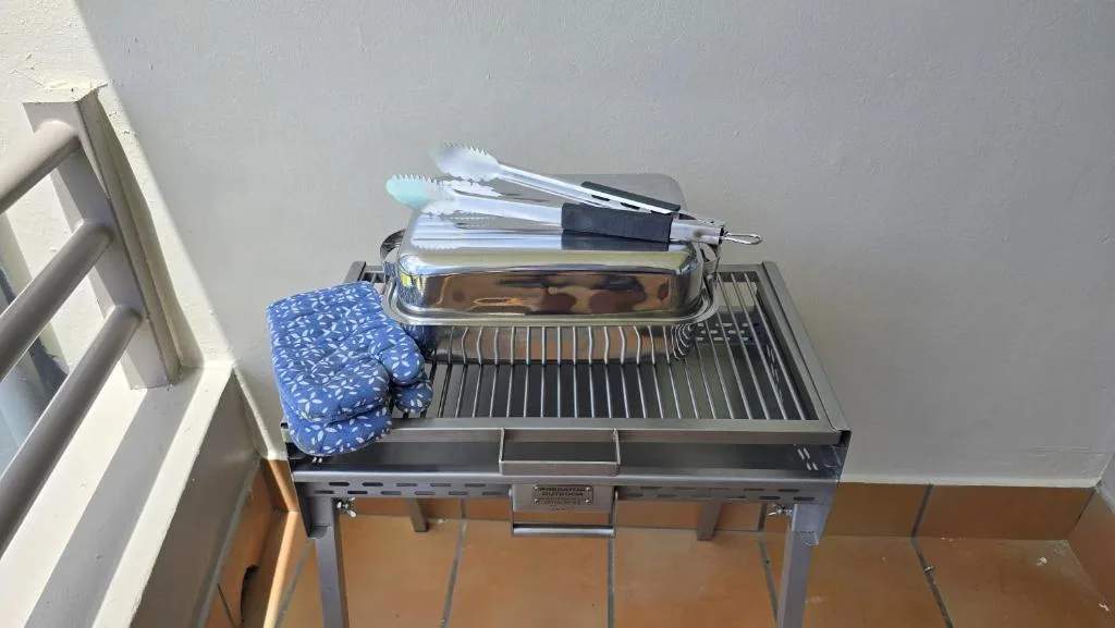 Outdoor braai grill with tongs and oven mitts ready for use