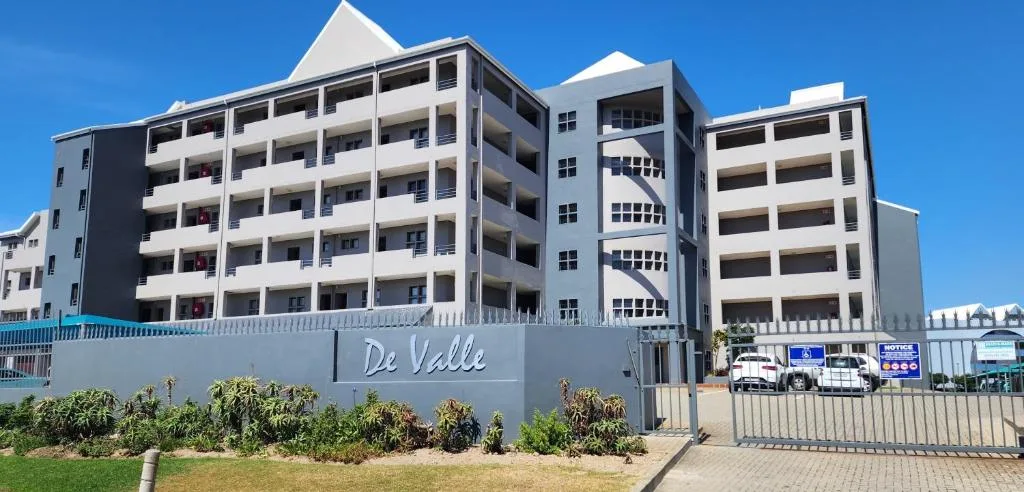 Modern white apartment building with multiple balconies under clear blue sky