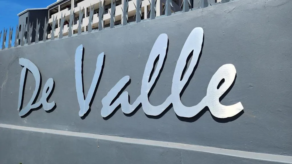 De Valle property signage on gray building facade with balconies above