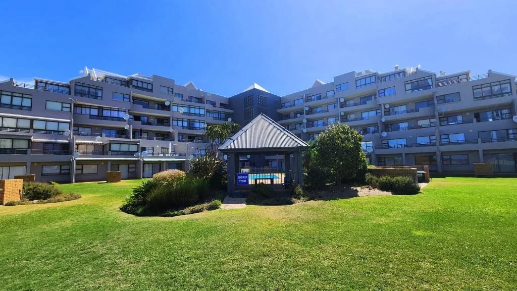 Modern apartment complex with manicured lawns and central courtyard pavilion