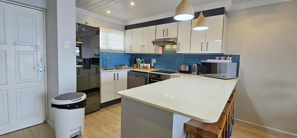 Modern kitchen with cream cabinetry, blue tile backsplash, and island counter