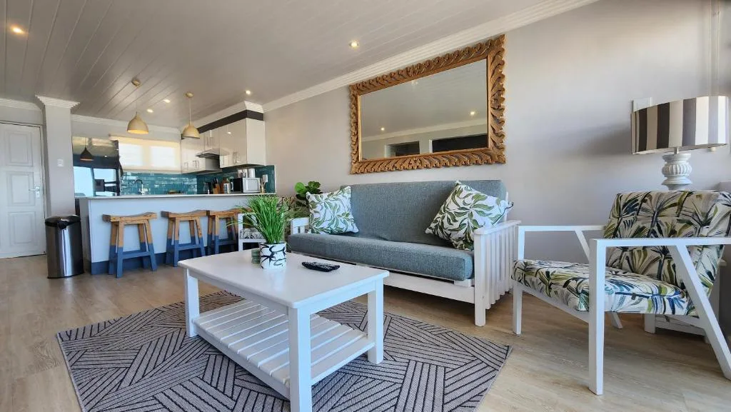 Bright open-plan lounge with grey sofa, white coffee table, and patterned armchairs