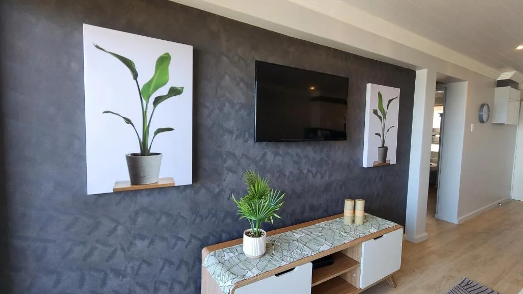 Modern lounge with dark accent wall, TV, plant artwork, and wooden console table