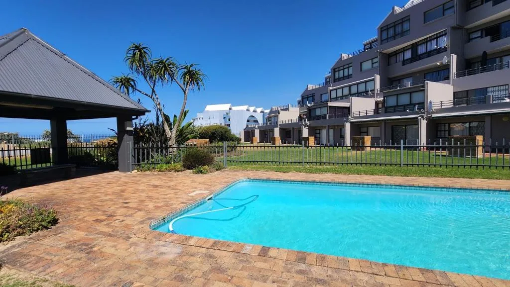 Bright blue swimming pool with brick paving and modern apartment buildings