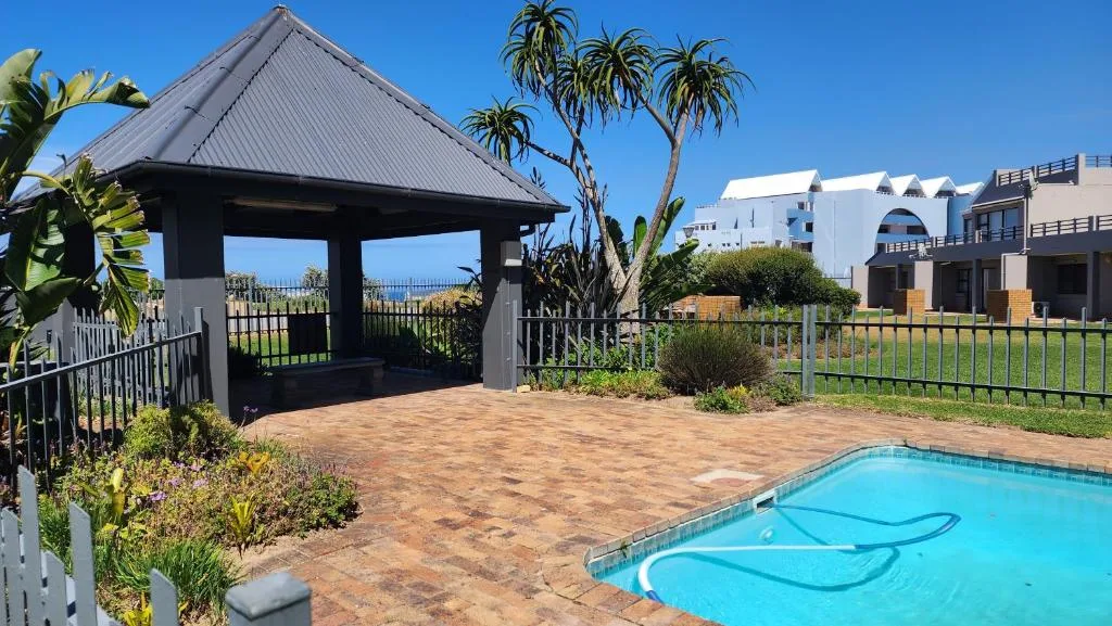 Bright blue swimming pool with gazebo and manicured gardens surrounding