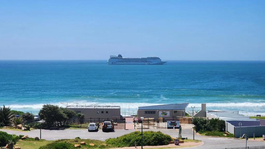 Ocean view with cruise ship on horizon and beachfront buildings below